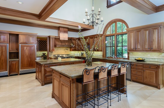 Two granite islands, one with a breakfast counter, offer additional storage and power, while rich cherry cabinetry, windows and ceiling beams lend warmth to the room. Built-in appliances include Viking gas stove with 8-burner cooktop and griddle, copper commercial vent, three ovens, two dishwashers, and separate SubZero refrigerator and freezer.
